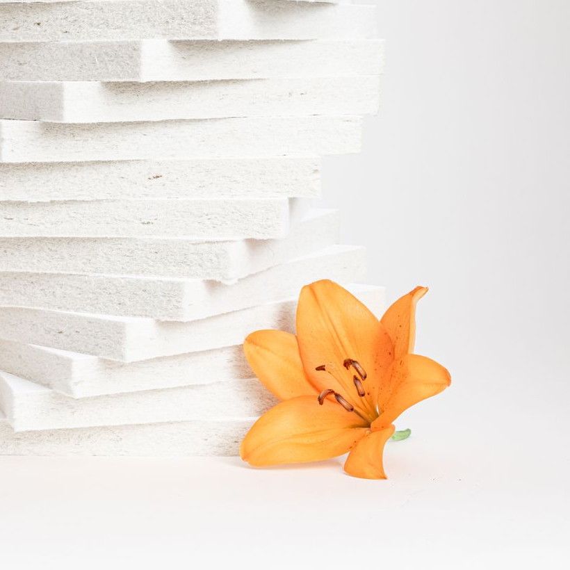A pile of Aisti acoustic tiles with an orange flower